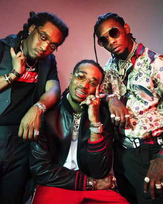 Three men in stylish outfits with sunglasses posing against a pink and red gradient background